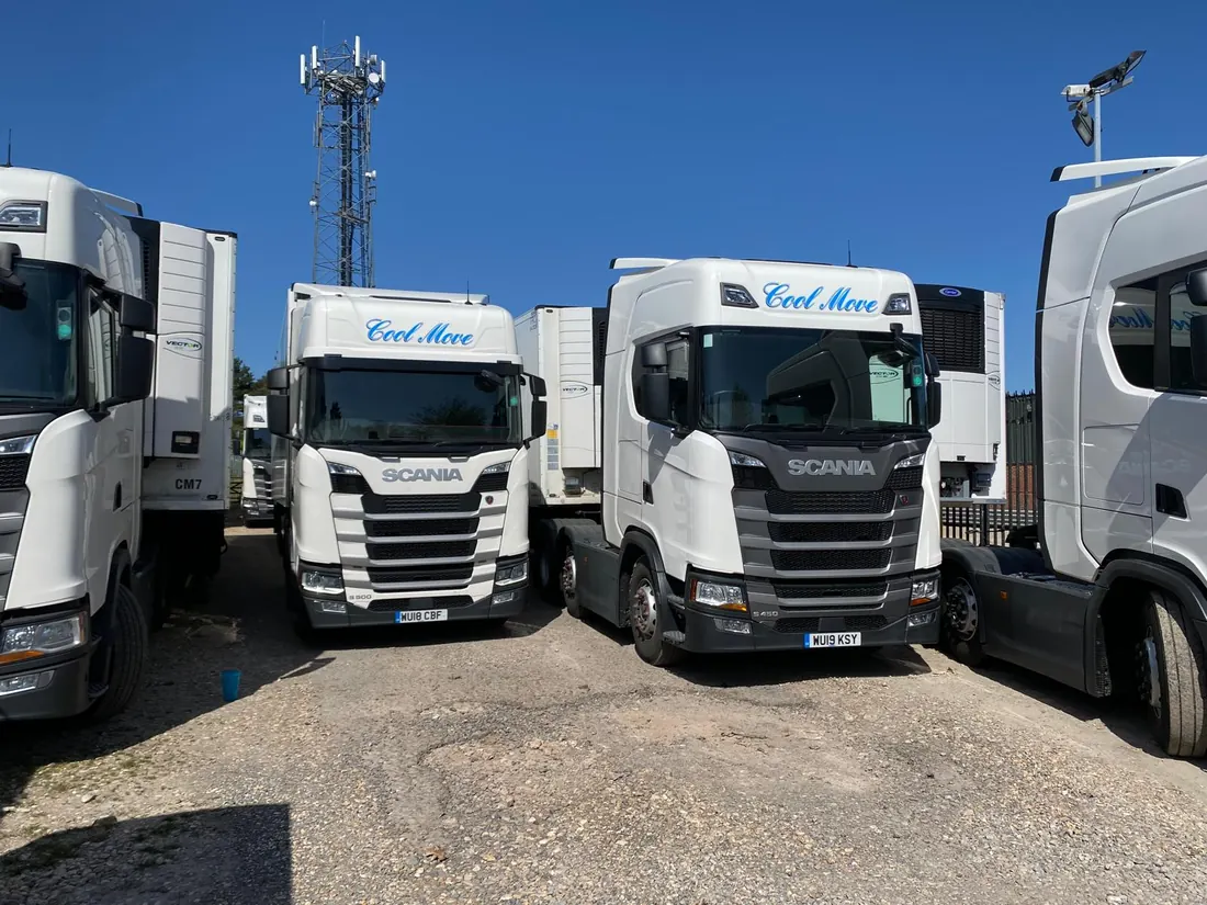 Two white Cool Move Scania tractor units coupled to Chereau reefer trailers, parked nose to tail on the operating yard.